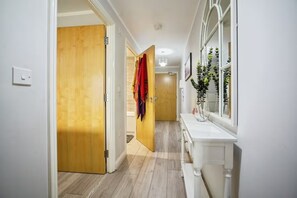 A hallway with wooden doors, a white vanity with a mirror, and a plant. - Apartment Sleeps 4 with Balcony (Erith)