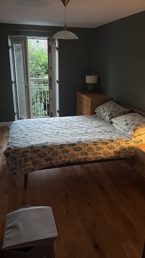 A bedroom with a bed, a nightstand, a lamp, and a window with blinds. - One Double Room in Holyrood Apartment (Edinburgh)