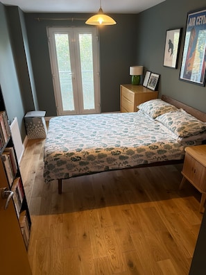 A bedroom with a bed, a nightstand, a lamp, a window with blinds, and a bookshelf. - One Double Room in Holyrood Apartment (Edinburgh)
