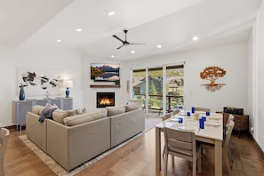 A modern living room with a fireplace, a dining area, and a large window with a view of the outdoors. - Black Rock Ridge 14457  (Hideout)