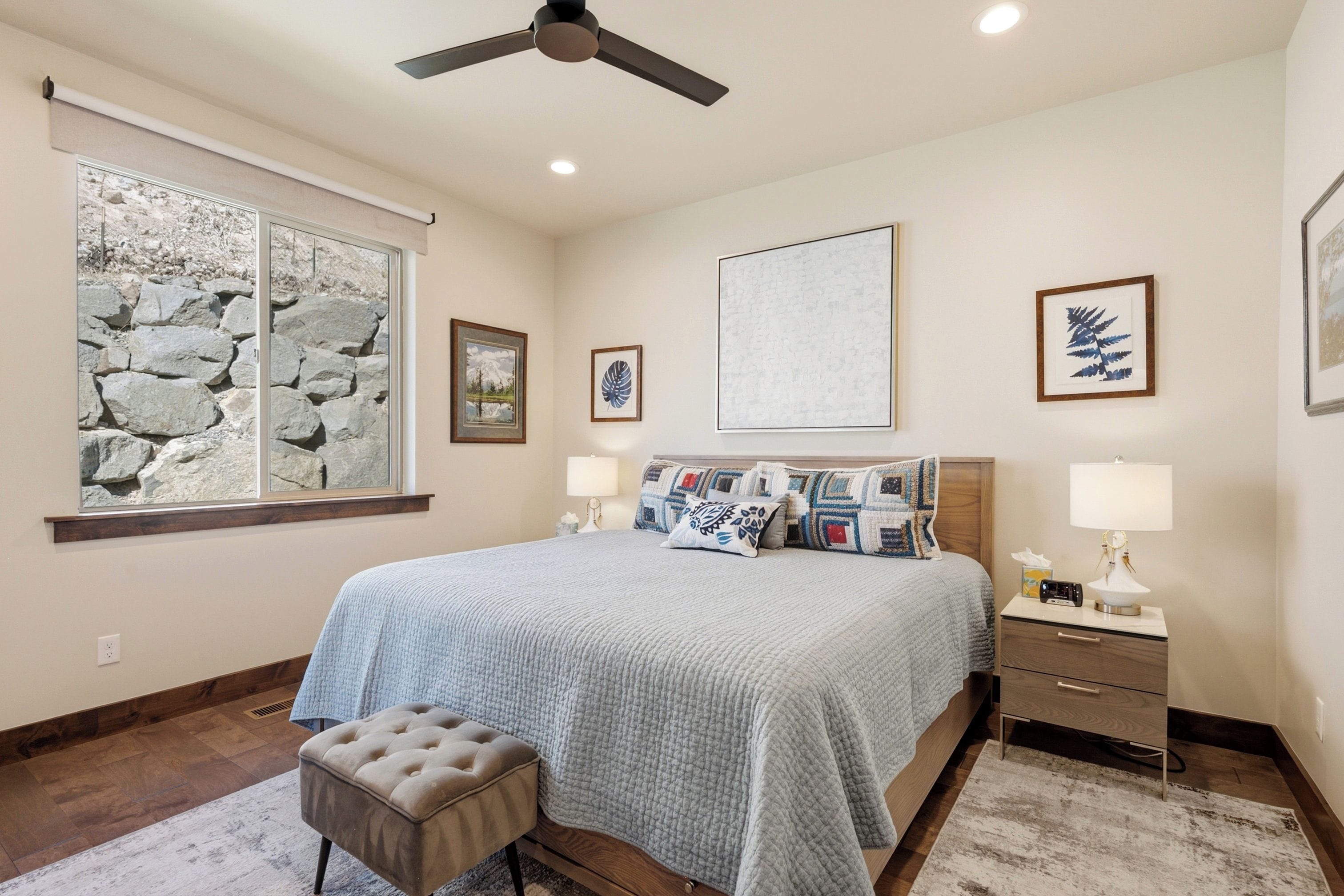 A bedroom with a bed, bedside tables, a bench, and artwork on the walls.