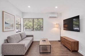 A modern living room with a sofa, a coffee table, a TV, and a wooden cabinet. - Newly Renovated 1BR | Near Beach & Downtown Unit 1 (Hollywood)