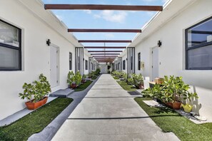 A corridor with potted plants and a concrete walkway. - Newly Renovated 1BR | Near Beach & Downtown #3 (Hollywood)