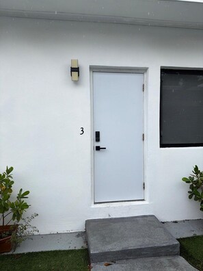 A white door with a number '3' on the wall, a small step leading up to it, and two potted plants on either side. - Newly Renovated 1BR | Near Beach & Downtown #3 (Hollywood)