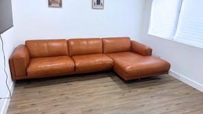 A brown leather sectional sofa in a room with wooden flooring and white walls. - Newly Renovated 1BR | Near Beach & Downtown Unit 2 (Hollywood)