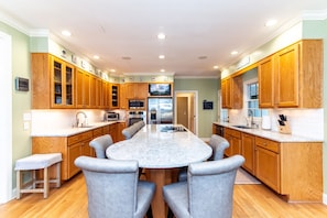 A modern kitchen with wooden cabinets, a granite countertop, and a central island with seating. - Cheehaw Paradise | 2 Min Beach Walk | Elevator | Dual King Suites | Sleeps 14 | Dog Friendly (Edisto Beach)