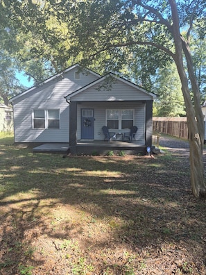 A single-story house with a porch, a front door, and a small window. - Cozy 2-bedroom bungalow in delightful Anderson with AC (Anderson)