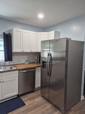 A modern kitchen with stainless steel appliances, white cabinetry, and a wooden countertop. - Cozy 2-bedroom bungalow in delightful Anderson with AC (Anderson)