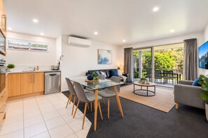 A modern apartment with a kitchen, dining area, living room, and a balcony with a view. - Alpine Retreat | 2-Bedroom Apartment with Pools, Hot Tub, Gym & Resort Facilities (Wānaka)