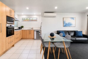 A modern kitchen with wooden cabinets, a built-in oven, and a dishwasher. - Alpine Retreat | 2-Bedroom Apartment with Pools, Hot Tub, Gym & Resort Facilities (Wānaka)