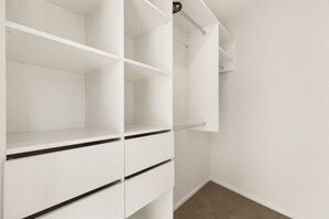 A white closet with open shelves and a hanging rod. - Modern Wānaka Retreat | 3 Queen Bedrooms, Mountain Views, High Ceilings & Internal Garage (Wānaka)