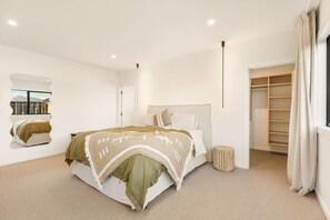 Ein modernes Schlafzimmer mit einem großen Bett, einem begehbaren Kleiderschrank und einem Fenster mit Blick.