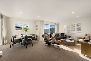 A spacious living area with a dining table, chairs, a sofa, and a coffee table. - Mountain View House | 3 Bedrooms, Sleeps 6, 2 Bathrooms, Air Conditioning & Easy Access to Lake Wānaka (Wānaka)