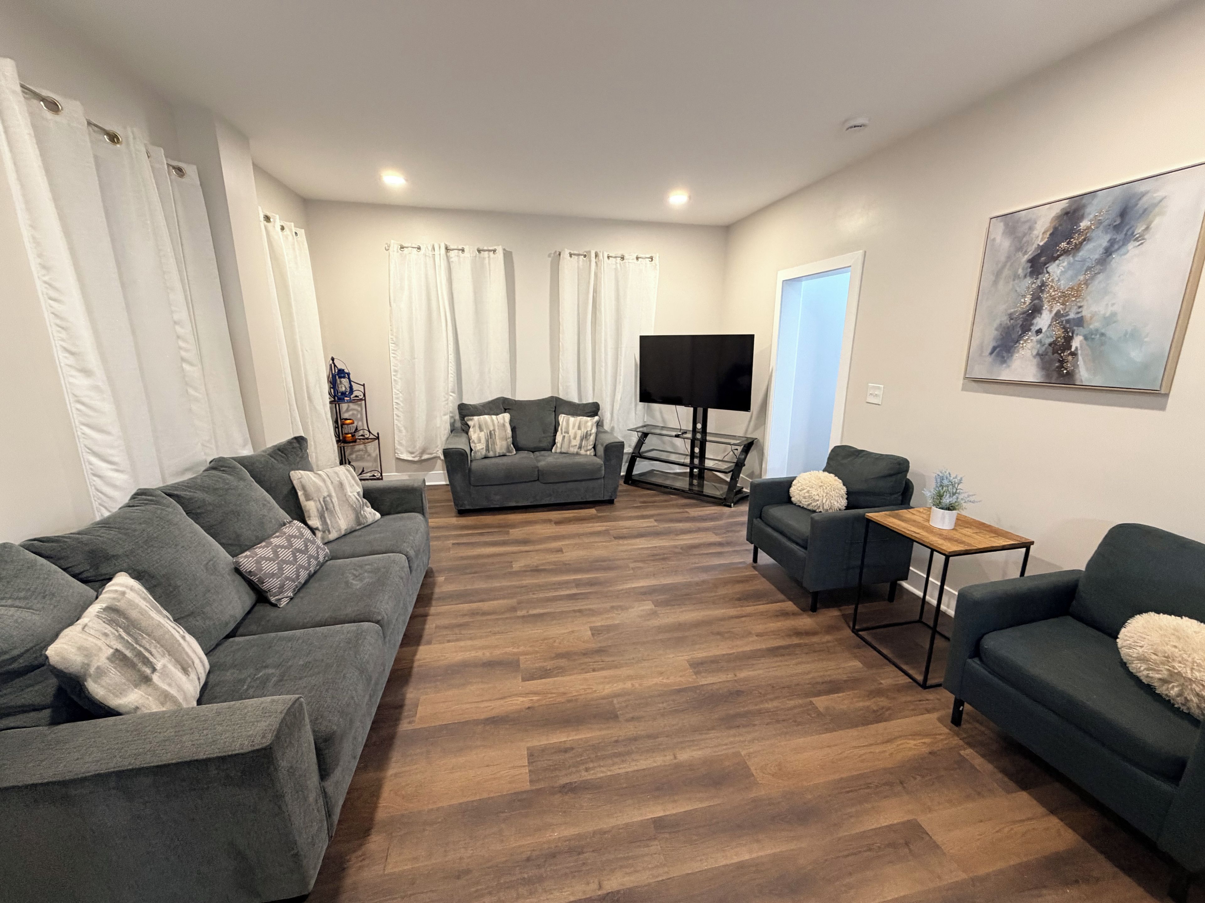A living room with a grey sofa set, a coffee table, and a flat-screen TV.