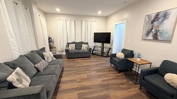 A living room with a grey sofa set, a coffee table, and a flat-screen TV.