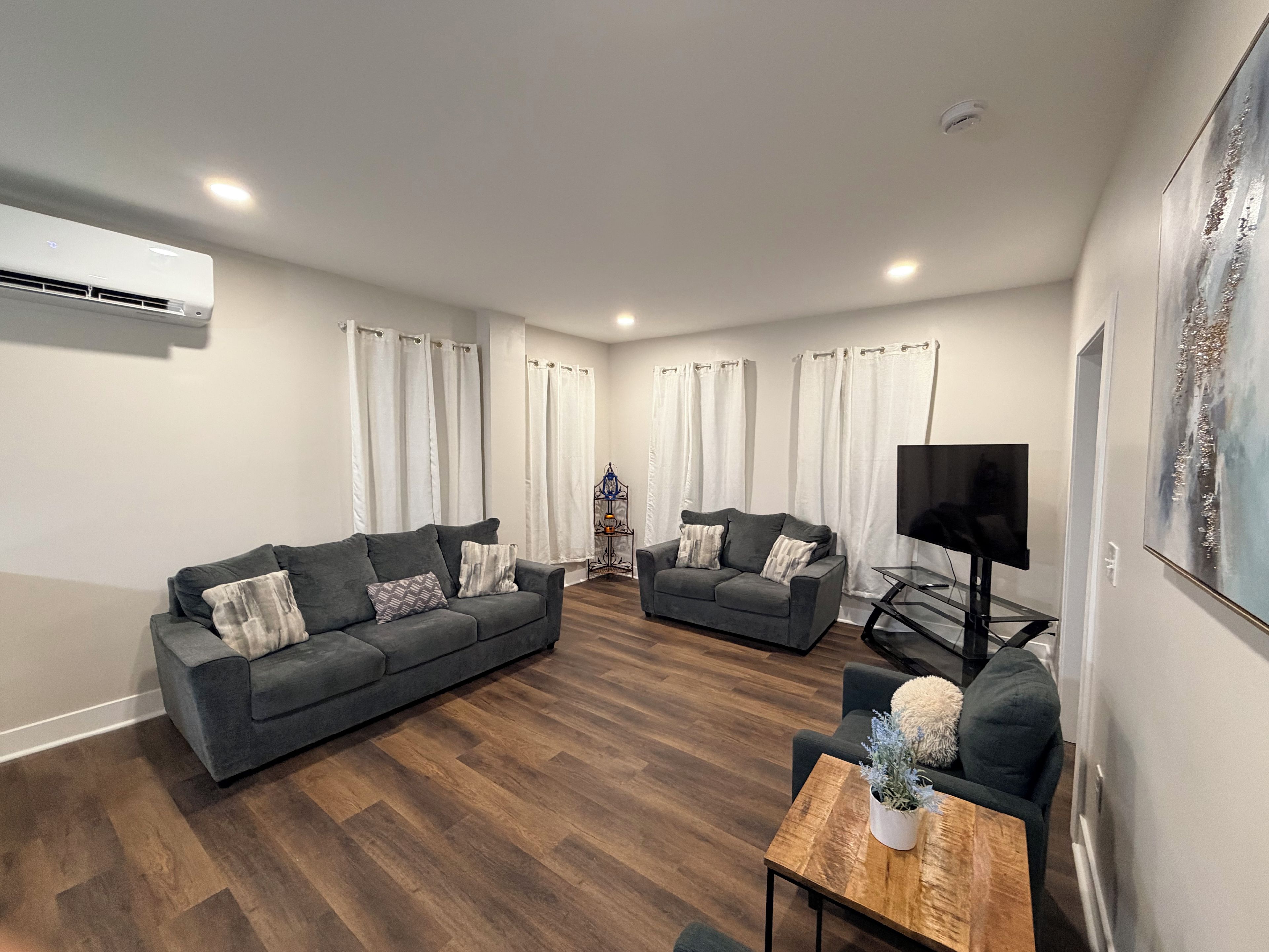 A modern living room with two sofas, a coffee table, a TV, and a painting on the wall.