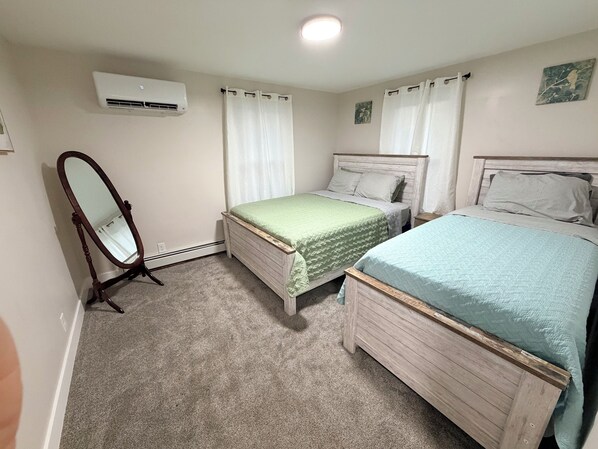 A bedroom with two beds, a mirror, and an air conditioning unit.