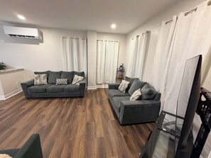 A modern living room with two grey sofas, a flat-screen TV, and a wooden floor. - Delightful 4-bedroom house in Carneys Point Township, near Wilmington & Philly! (Carneys Point Township)