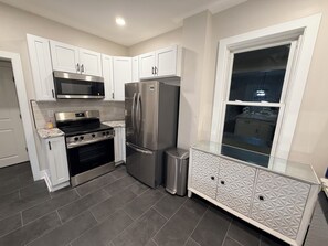 A modern kitchen with white cabinets, stainless steel appliances, and a patterned glass cabinet. - Delightful 4-bedroom house in Carneys Point Township, near Wilmington & Philly! (Carneys Point Township)