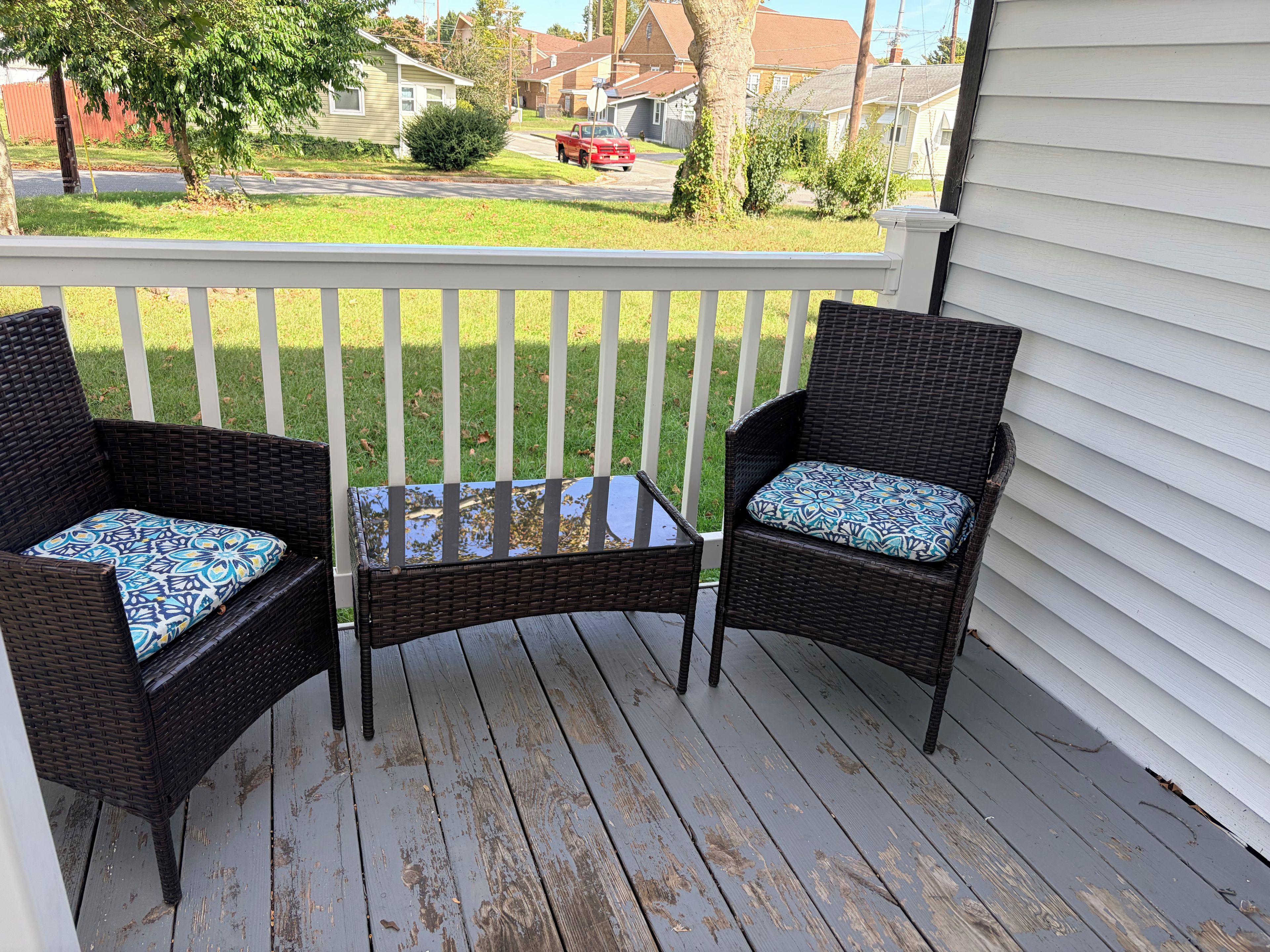 A porch with two wicker chairs and a small table.