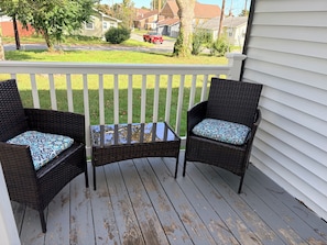 A porch with two wicker chairs and a small table.