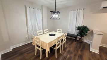 A dining area with a wooden table and chairs, a pendant light, and a bench.