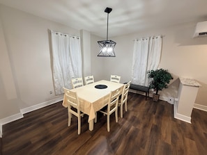 Un coin repas avec une table et des chaises en bois, un luminaire suspendu et un banc.