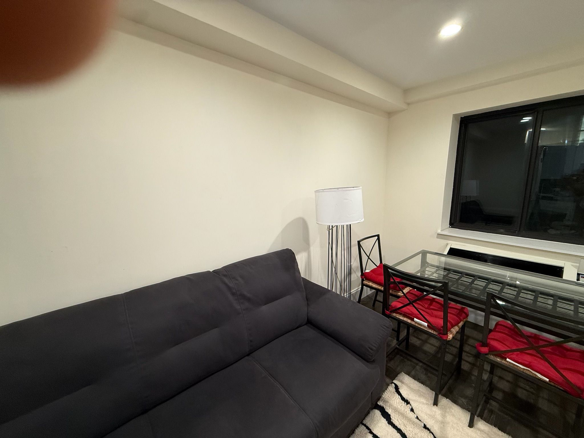 Een moderne woonkamer met een zwarte bank, een glazen salontafel en rode kussens.