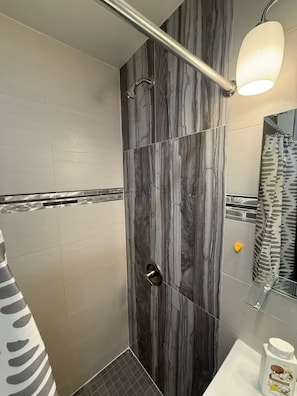 Ducha con puerta de vidrio, perchero, espejo y cortina.