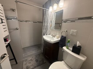 Een badkamer met douche, toilet, wastafel en een handdoekrek.