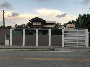 A modern building with a gated entrance, a covered walkway, and a visible balcony. - House with Pool in Bombinhas (Bombinhas)