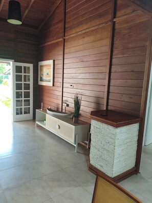 A room with wooden walls, a white cabinet with a sink, a door leading outside, and a framed picture on the wall. - House with Pool in Bombinhas (Bombinhas)