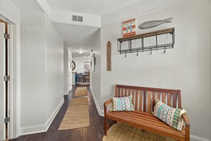 A hallway with a wooden bench, a wall-mounted rack, and a sign. - Enjoy Endless Views  at Beachfront Condominium! (St. Simons Island)
