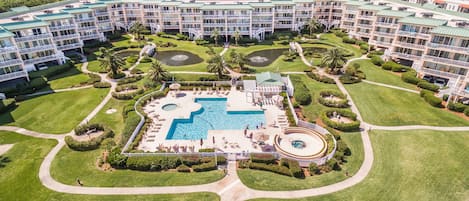 A resort with multiple buildings, a central swimming pool, and well-maintained lawns.