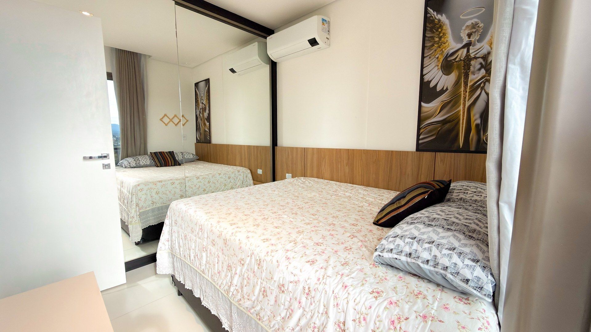 Habitación de hotel con dos camas, un espejo grande y un equipo de aire acondicionado.