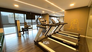 Ein Fitnessstudio mit Laufbändern, Kraftgeräten und einer Wand mit einer Trainingsillustration.