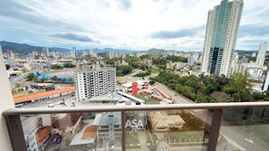 Un paisaje urbano con una combinación de edificios altos y construcciones más pequeñas, cielo despejado y una vista de una calle con vehículos.