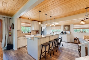 A spacious kitchen with a large island, wooden ceiling, and pendant lighting. - Paradise Cove - Lake View, Dock, Near Yosemite (Bass Lake)