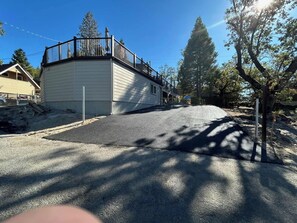 A residential area with a house featuring a balcony, a driveway, and surrounding trees. - Paradise Cove - Lake View, Dock, Near Yosemite (Bass Lake)