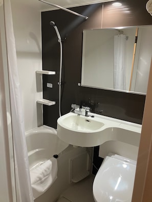 A compact bathroom with a white sink, a mirror, a shower, and a toilet. - Smile Hotel Kagoshima-chuo Ekimae (Kagoshima/Nishida)