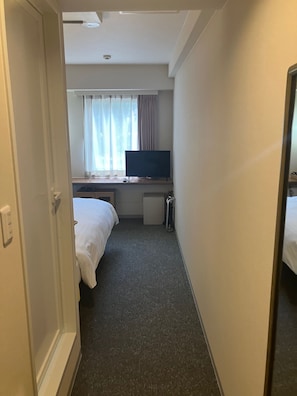 A hotel room with a bed, a desk with a television, a window with curtains, and a carpeted floor. - Smile Hotel Kagoshima-chuo Ekimae (Kagoshima/Nishida)