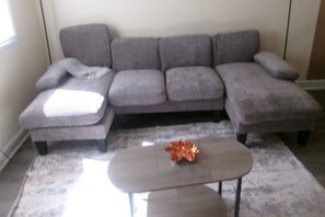 A grey sectional sofa with a matching ottoman and a decorative item on the ottoman. - 3 bedroom one bathroom in High point N.C. near HPU, (High Point)