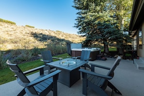 Eine Außenpatio mit Tisch und Stühlen, einem Whirlpool und Blick auf eine Hügelkuppe.