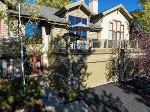 A two-story house with a balcony, a garage, and a stone foundation. - 4BR Park Meadows townhome with mountain views, sleeps 10 (Park City)