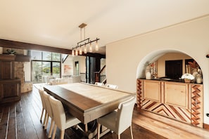 A spacious dining area with a wooden table and chairs, a kitchen with a herringbone-patterned backsplash, and a view through a glass door. - 4BR Park Meadows townhome with mountain views, sleeps 10 (Park City)