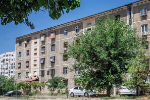 A multi-story building with a row of windows, some balconies, and a tree in the foreground. - Apartments in the historic center (Tashkent)