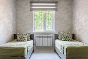 Huoneessa on kaksi sänkyä, ikkuna ja patteri.