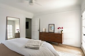 A bedroom with a bed, dresser, mirror, and a door leading to another room. - Casa Mika - Designer Curated 2BR/1BA Retreat Near SoFi, Intuit Dome & The Forum (Los Angeles)