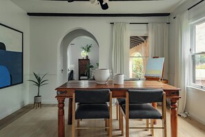 A dining area with a wooden table, two chairs, a coffee pot, and a white pitcher. - Casa Mika - Designer Curated 2BR/1BA Retreat Near SoFi, Intuit Dome & The Forum (Los Angeles)