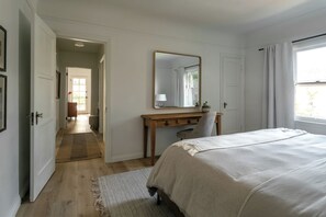 A bedroom with a bed, a desk, a chair, a mirror, and a window. - Casa Mika - Designer Curated 2BR/1BA Retreat Near SoFi, Intuit Dome & The Forum (Los Angeles)